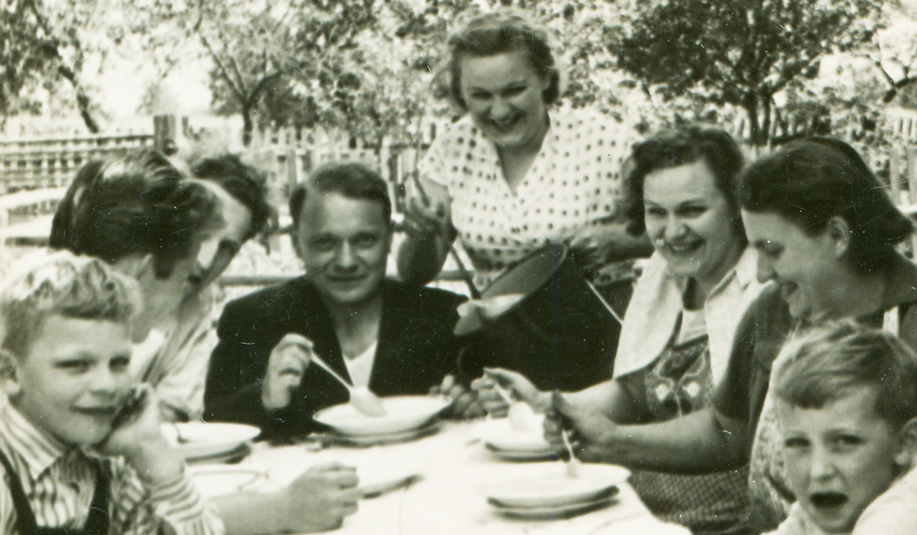 Sort-hvidt billeder af familie omkring bordet i haven